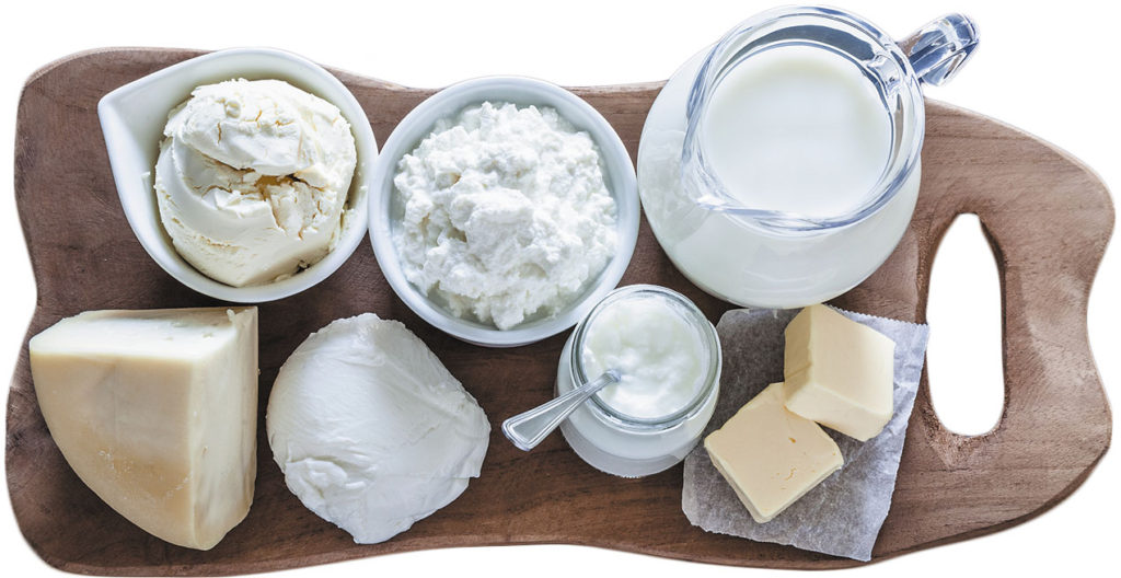 Dairy products assortment shot from above on bluish tint kitchen table. The products are arranged on a rustic wooden cutting board. Dairy products included are milk, yogurt, butter, mozzarella, mascarpone, ricotta and hard cheese. DSRL studio photo taken with Canon EOS 5D Mk II and Canon EF 100mm f/2.8L Macro IS USM